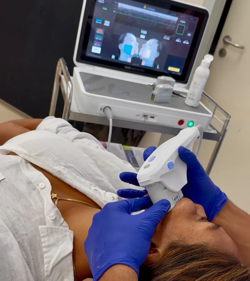 Tratamiento Ultherapy PRIME en cuello y mandíbula con el equipo y su pantalla al fondo, en la cabina del centro.